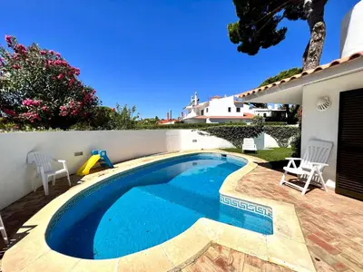 a swimming pool with two chairs and a house at Vilamoura Traditional Villa with Pool by Homing in Vilamoura