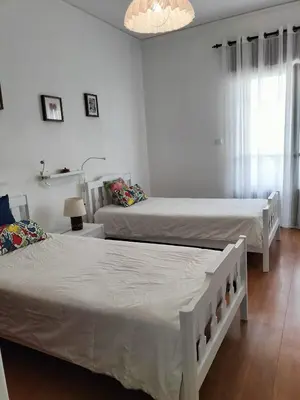two beds in a room with white walls at T2-MAMAMIA II Frente Mar in Quarteira