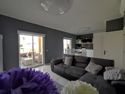 a living room with a couch and a kitchen at Casa das Oliveiras o seu refugio no Algarve in Quarteira