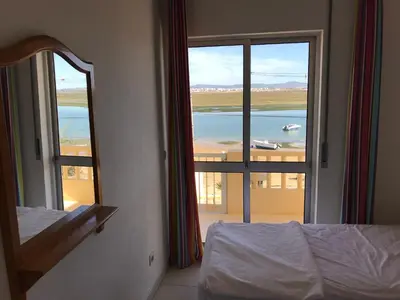 a bedroom with a bed and a view of the ocean at Apartamentos Barracuda in Faro