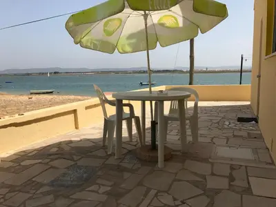 a table and chairs under an umbrella on the beach at Apartamentos Barracuda in Faro