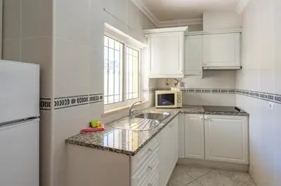 a kitchen with white cabinets and a sink at Torre da Aldeia by Umbral in Albufeira