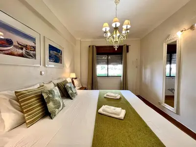a bedroom with a large white bed with a green rug at Albufeira Cosy by Homing in Albufeira