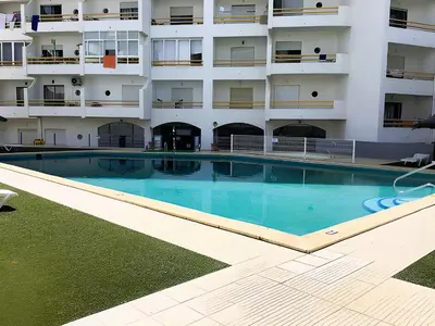 an empty swimming pool in front of a building at 1 Bedroom Apartment Chaves, Praceta Vitorino Nemesio, Albufeira in Albufeira