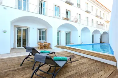 a patio with two chairs and a swimming pool at Vacation Time Apartment in Faro