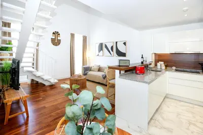 a kitchen and living room with white walls and wooden floors at Vacation Time Apartment in Faro