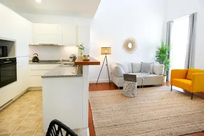 a kitchen and a living room with a couch at Querido Algarve Apartment in Faro