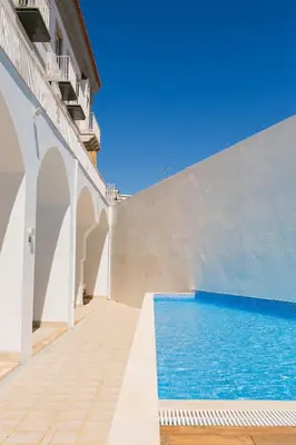 a house with a swimming pool and a white wall at Querido Algarve Apartment in Faro