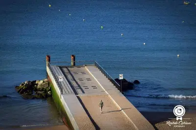 a pier in the ocean with a person walking on it at Casa Docim, casa tipica algarvia no centro da cidade velha in Albufeira