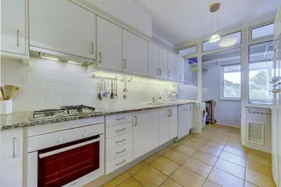 a kitchen with white cabinets and a red fireplace at Vila Sol Apartamento fantástico 3 quartos piscina in Quarteira