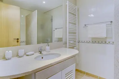 a white bathroom with a sink and a mirror at Vila Sol Apartamento fantástico 3 quartos piscina in Quarteira