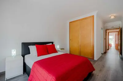 a bedroom with a large bed with a red blanket at V3 Olhos dÁgua com piscina AC wifi 800m praia in Olhos de Água