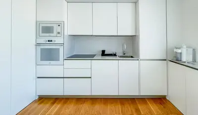 a white kitchen with white appliances and wooden floors at Penthouse Triplex com Jacuzzi T3 HsR Vilamarina in Vilamoura