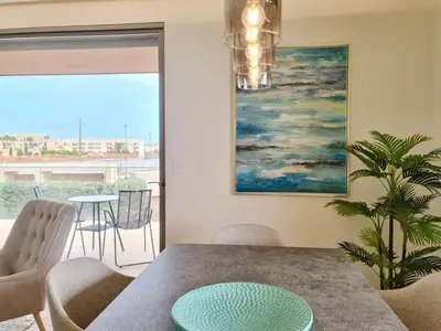 a dining room with a table and chairs and a painting at La Vila Nature, Laguna Village 246-Clever Details, Luxury apartment, located in a quiet area, BBQ and free Wi-Fi in Vilamoura