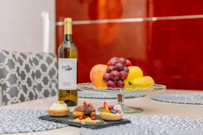 a bottle of wine and a plate of fruit on a table at Monicca Collection Suites and Residences in Albufeira