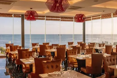 a restaurant with tables and chairs with the ocean in the background at Monicca Collection Suites and Residences in Albufeira