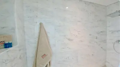 a white marble bathroom with a towel hanging on a wall at Villa Miya - Clever Details, walking distance from the Marina, restaurants, bakeries and supermarkets,, free wifi, pool in Vilamoura