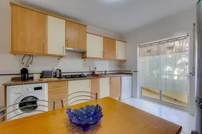 a kitchen with wooden cabinets and a wooden table at JAZZ & SILVIA - Moderno & Central apenas a 5 min da praia dos Pescadores in Albufeira
