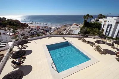 a swimming pool with chairs and the ocean in the background at Excellent Sea view 1 Bedroom Apartment, Verandas do Mar, Olhos de Agua AT05 in Olhos de Água