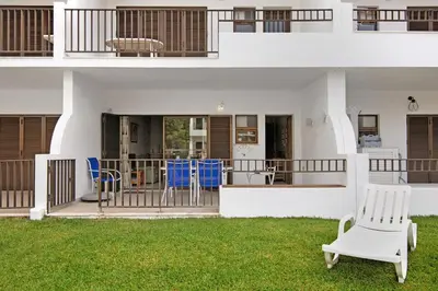 a white house with blue chairs on the front porch at Mouramar Vilamoura in Vilamoura