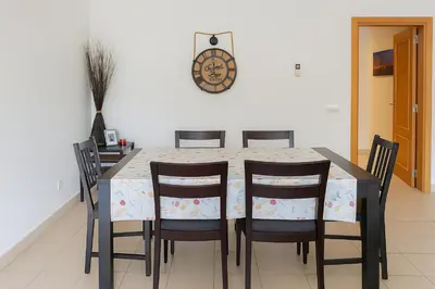 a dining room table with chairs and a clock on the wall at Kasa Joly Albufeira By Calyferias in Albufeira