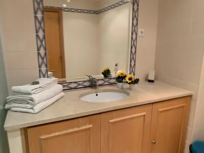 a bathroom with a sink with a mirror and towels at Kasa Joly Albufeira By Calyferias in Albufeira