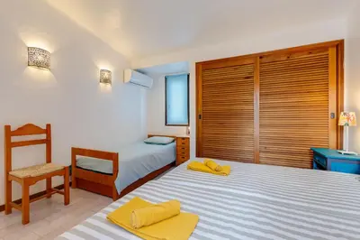 a bedroom with two twin beds and a chair at CASA NINI - Apart para 6 com AC e a 100 m da praia Mónica Isabel in Albufeira