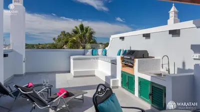 a patio with chairs and a grill on a white building at Apartment Kairi in Vale do Lobo