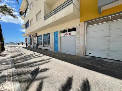 a building with two garage doors on a street at Infante Sagres by FHR1º linha da praia in Quarteira