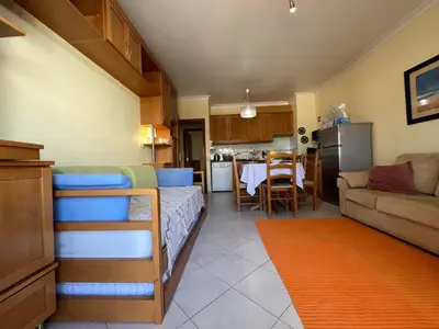 a kitchen and a living room with a bed and a couch at Infante Sagres by FHR1º linha da praia in Quarteira