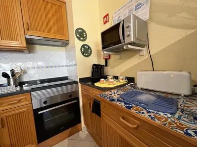 a small kitchen with a stove and a counter top at Infante Sagres by FHR1º linha da praia in Quarteira
