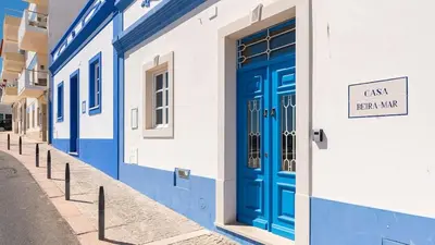 a blue and white building with a blue door at Refurbished beachfront house, Pool, AC, WiFi, Albufeira, sea view in Albufeira
