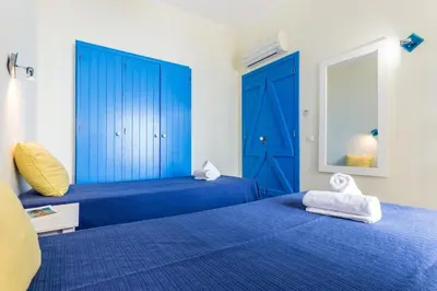 a bedroom with two blue beds and a mirror at Refurbished beachfront house, Pool, AC, WiFi, Albufeira, sea view in Albufeira
