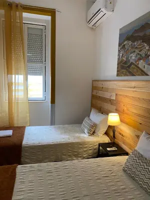 a hotel room with two beds and a window at The Tiles House in Faro