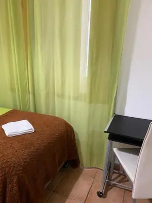 a room with a bed and a table and a green curtain at The Tiles House in Faro