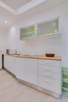 a white kitchen with a counter and two windows at Marina Star Guesthouse in Faro