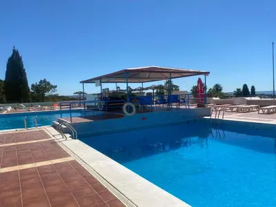 a large swimming pool with a gazebo with blue water at Ana Sun in Albufeira