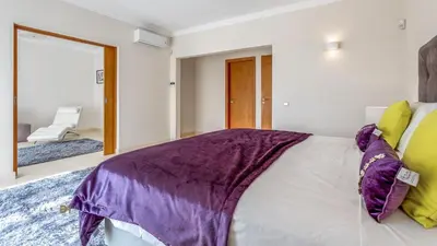 a bedroom with a large bed with purple and yellow pillows at Luxuosa moradia V5 em Quarteira - Greice Homes in Quarteira