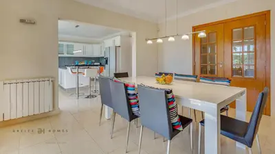 a kitchen and dining room with a white table and chairs at Luxuosa moradia V5 em Quarteira - Greice Homes in Quarteira