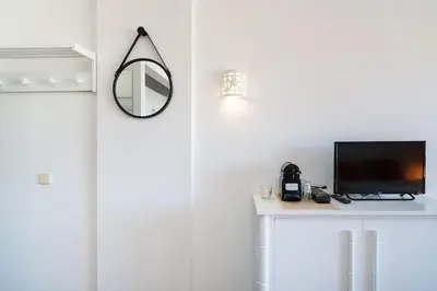 a room with a tv on a table with a mirror at SILCHORO - Estúdio remodelado com AC e piscina in Albufeira