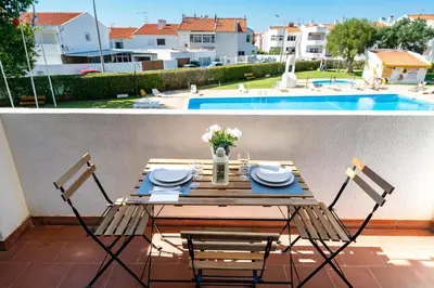 a table and chairs on a balcony with a pool at SILCHORO - Estúdio remodelado com AC e piscina in Albufeira