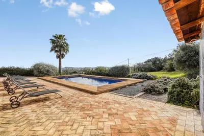 a patio with a bench and a swimming pool at Casa de Apra by Portucasa in Loulé