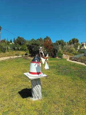 a bird feeder on a stump in the grass at Casa de Apra by Portucasa in Loulé
