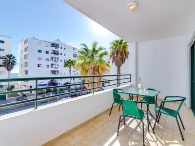a balcony with a table and chairs and palm trees at AL - Apartamento Pérola in Quarteira