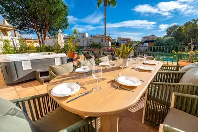 a wooden table with plates and wine glasses on a patio at Place in the sun - Free out door Jacuzzi - BY BEDZY in Albufeira