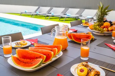 a table with plates of fruit and juice next to a pool at Villa Coral Bay by Algarve Vacation in Albufeira