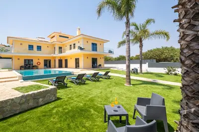 a villa with a swimming pool and palm trees at Villa Coral Bay by Algarve Vacation in Albufeira