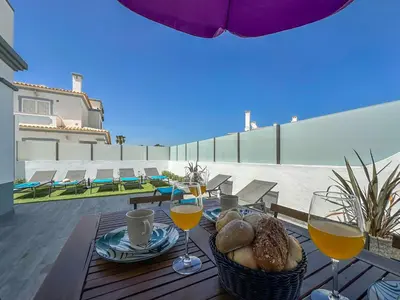 a table with glasses of wine and bread on a patio at Luxury Villa walking distance Galé Beach Albufeira in Albufeira