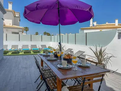 a wooden table with a purple umbrella on a patio at Luxury Villa walking distance Galé Beach Albufeira in Albufeira