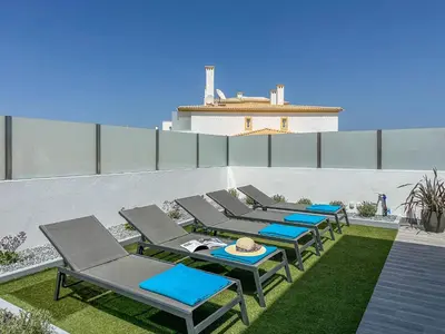 a row of chaise lounges and chairs on a patio at Luxury Villa walking distance Galé Beach Albufeira in Albufeira